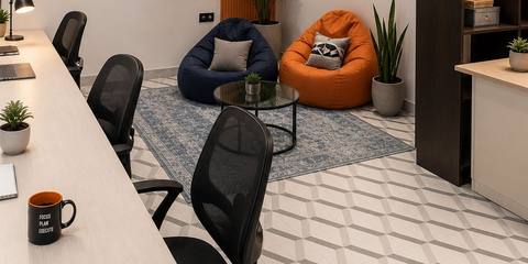 Corner with a navy bean bag and an orange bean bag, framed posters on the wall and a desk with black chairs