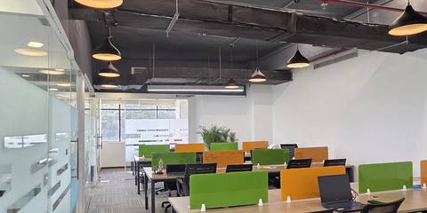 Open workspace with green and orange desk dividers and black pendant lamps under an exposed ceiling at Livance NH-8